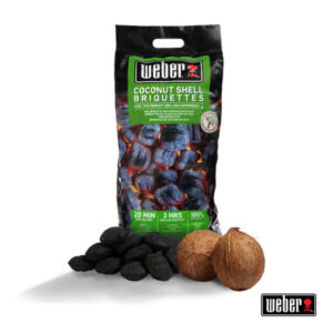 Eine Packung Weber Coconut Shell Briquettes mit Abbildung glühender Briketts. Vor der Packung liegen mehrere schwarze Briketts und zwei Kokosnüsse. Unten rechts ist das Weber-Logo zu sehen.