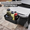 Ein schwarzer Weber Works Gewürz- und Saucenhalter ist an einem Grill befestigt und enthält verschiedene Gewürze und Saucen. Der Text "Saucen & Gewürze GRIFFBEREIT" ist über dem Halter eingeblendet. Rechts unten ist eine stilisierte graue Flamme abgebildet.