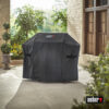 Ein Weber Premium Cover für die Spirit II 300 und E-210 Serien bedeckt einen Grill auf einer Terrasse