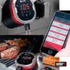 Weber iGrill Mini Bluetooth Thermometer neben einem Smartphone, das die zugehörige App mit Temperaturanzeigen anzeigt, während Fleisch und Spieße auf einem Grill in Bregenz, Vorarlberg, Österreich, zubereitet werden.